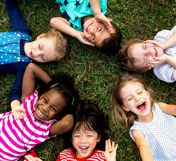 Des enfants souriants couchés en cercle dans l'herbe