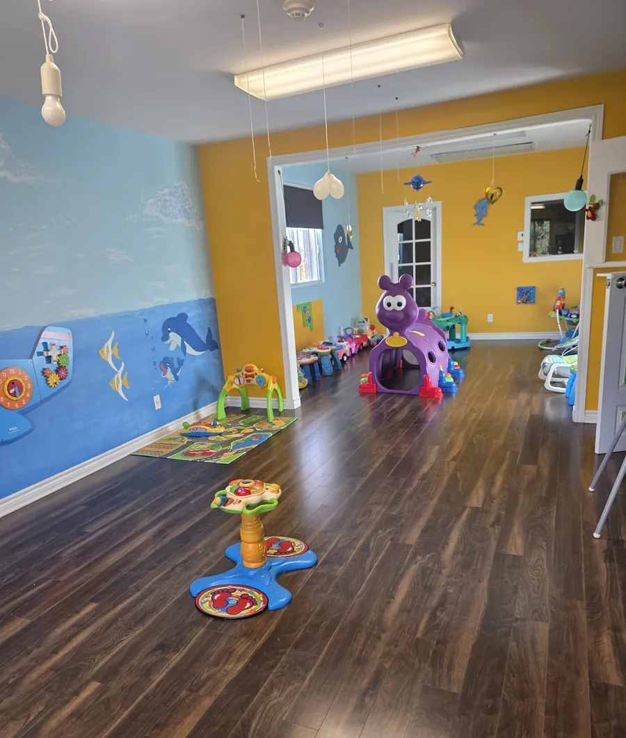 La pouponnière : un grand local avec un plancher de bois, une murale de l'océan et des jouets d'éveil