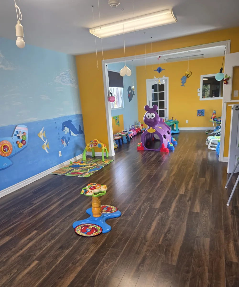 Le local de la pouponnière, lumineux, avec des jouets et un plancher de bois