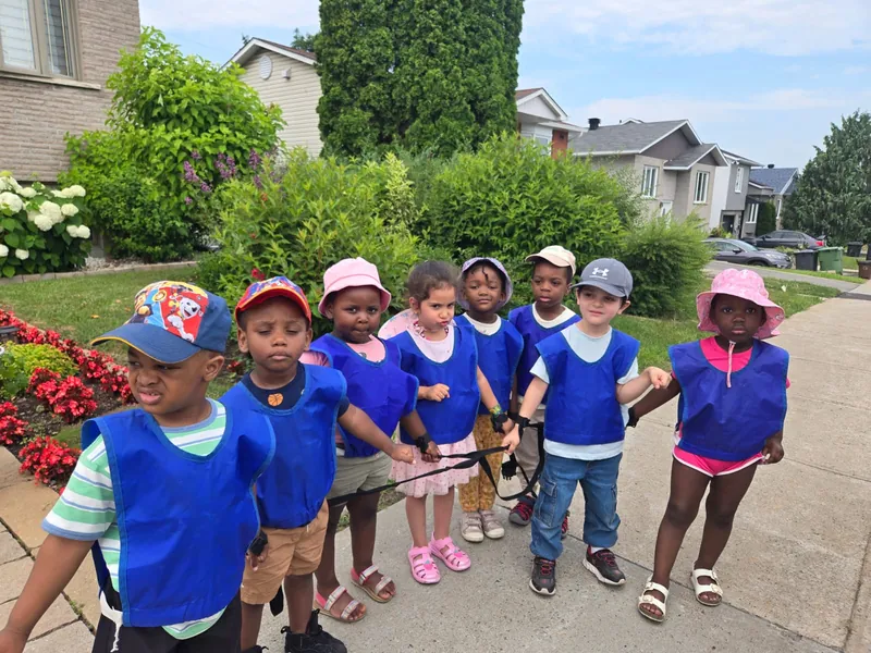 Un groupe d'enfants en dossards bleus pose sur le trottoir pendant une promenade